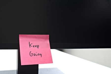 Keep Going sticky note left on a monitor. The bright note stands out against the monitor,...