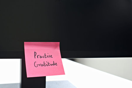 Practice Gratitude sticky note left on a monitor. The bright note stands out against the monitor,...