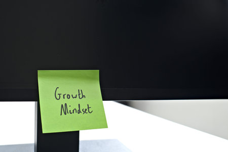 Growth Mindset sticky note left on a monitor. The bright note stands out against the monitor,...
