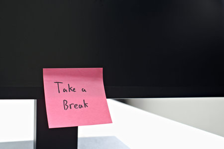 Take a Break sticky note left on a monitor. The bright note stands out against the monitor,...