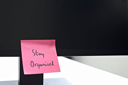 Stay Organized sticky note left on a monitor. The bright note stands out against the monitor,...