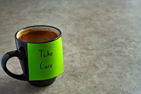Take Care sticky note left on a mug. The bright note stands out against the mug, symbolising motivation, productivity, and a focused mindset.
