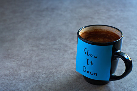 Slow It Down sticky note left on a mug. The bright note stands out against the mug, symbolising motivation, productivity, and a focused mindset.
