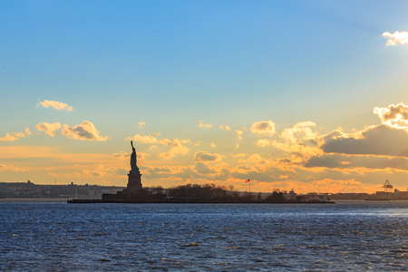 Statue of liberty with orange and yellow cloudscape.の写真素材