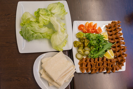 turkish cigkofte dish with lettuce, tomato, lemon,  parsley, and lavashの写真素材