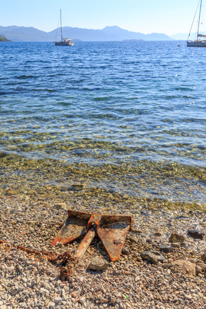 Rusted old anchor in the coastline of mediterranean seaの写真素材