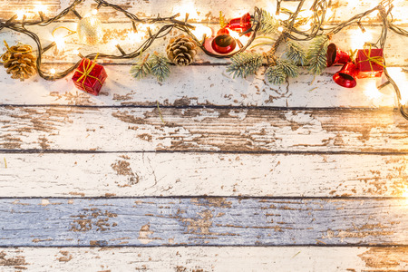 Christmas ornaments and pine branches on wooden table with yellow lights brightの写真素材