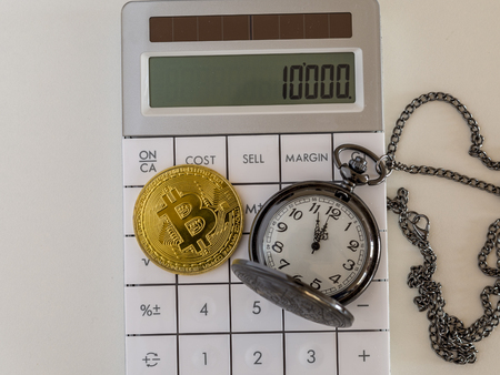 Golden bitcoin and pocket watch on calculator の写真素材