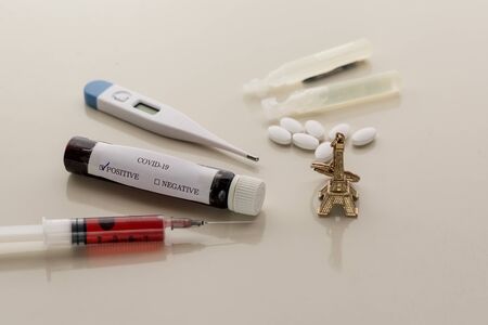 COVID-19 positive tube with Eiffel towel, syringe, thermometer, and pillsの写真素材