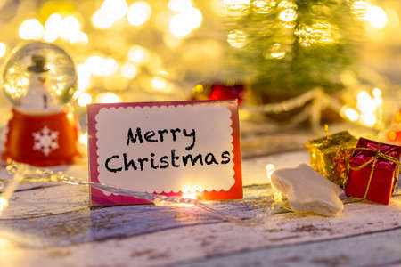 Merry Christmas writing on greeting card with decorations and lightsの写真素材