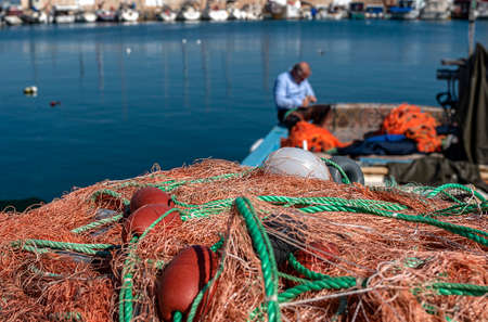 Fisherman repairing nets behind fishing netsの写真素材