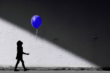Silhouette of a boy with a balloon on a white wallの写真素材