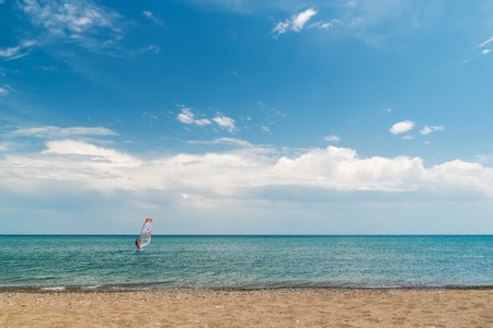 A quiet sea, blue sky, a surfer on the horizonの写真素材