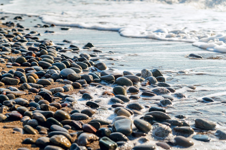 Beach, sea pebbles washed by the waves at sunriseの写真素材