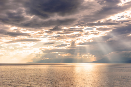 Sunset on the coast, the sun's rays pass through cloudsの写真素材