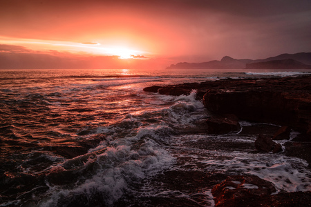 Storm sea at sunset on the south coast in red toneの写真素材