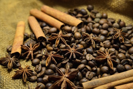 Coffee beans, cinnamon sticks, star anise on the background of old sacking, space for textの写真素材