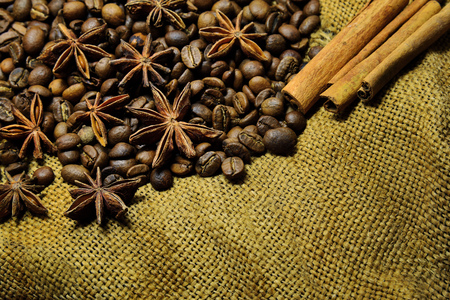 Coffee beans, cinnamon sticks, star anise on the background of old sacking, space for textの写真素材