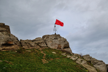 Red flag on top of a mountain against the background of a clear skyの写真素材