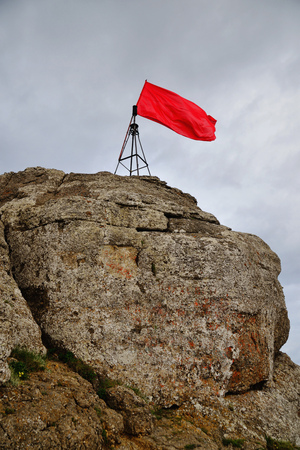 Red flag on top of a mountain against the background of a clear skyの写真素材