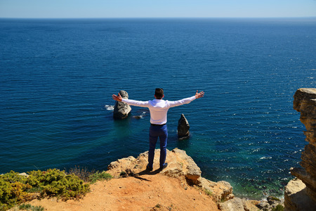 Open arms on the edge of the cliff against the blue seaの写真素材