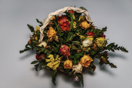 Basket with bouquet of dried roses on a white backgroundの写真素材