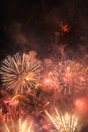 Explosion of multi-colored fireworks against the night sky on a holidayの写真素材