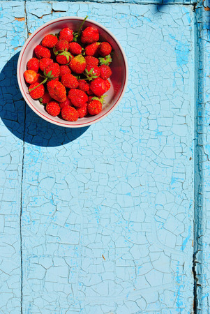 Ripe juicy red strawberry in a cup on a blue rustic backgroundの写真素材