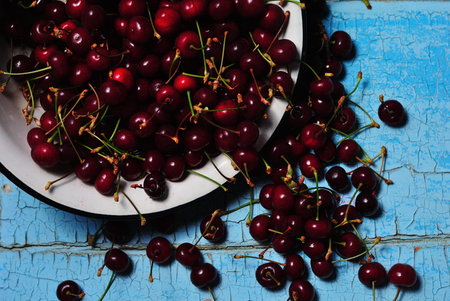Ripe juicy red cherry in a cup on a blue rustic background