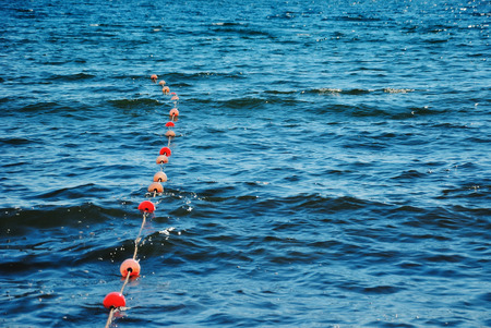 Restrictive life buoys on the blue sea surface on the coastの写真素材