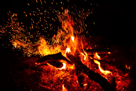 Large burning bonfire with soft glowing flame and sparkles flying all around