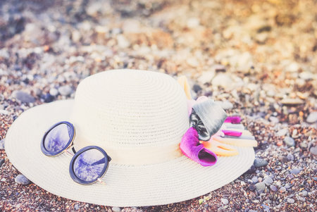 Straw hat with sunglasses on a sandy beach in summer