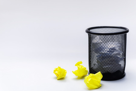 Basket with white and yellow crumpled notes on a white background, to the left is space for text, conceptual thinking, search for ideas, mistakeの写真素材