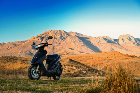 Moped on green grass in nature on a background of mountains on a sunny day, warm toningの写真素材