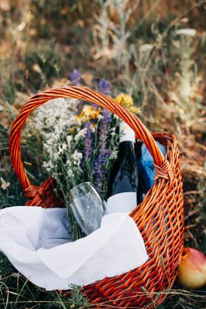 Fruit basket and wine on a plaid on the grass during a romantic picnic in the summer afternoonの写真素材