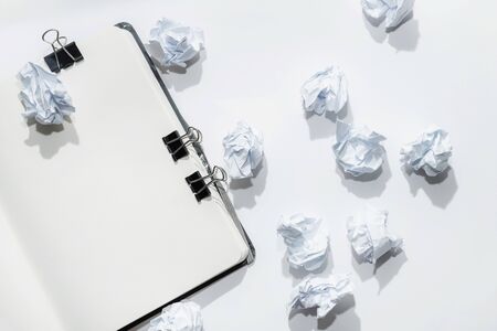 Opened notepad on a white background with crumpled papers scattered on the table, concept search, generation of ideasの写真素材