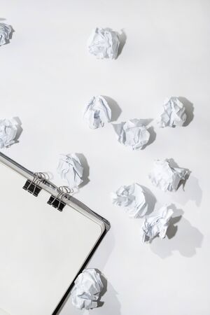Opened notepad on a white background with crumpled papers scattered on the table, concept search, generation of ideasの写真素材