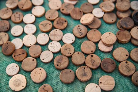 Wooden runes on green cloth on a table are randomly scatteredの写真素材
