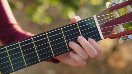Girl holds guitar in hand, hand and strings close-upの写真素材