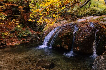 Beautiful waterfall in the autumn forest on a mountain streamの写真素材