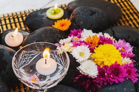 Wet black stones with chrysanthemum buds, decor for spa, relaxation and massageの写真素材