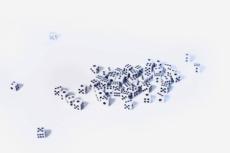A lot of little white playing cubes are randomly scattered on the tableの写真素材