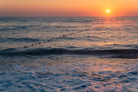 Beautiful sunny dawn in the clear sky on the sea coast during a stormの写真素材