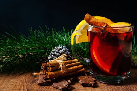 Glass with mulled wine on a wooden table with fir branches new year. Christmas decor with traditional hot winter drinksの写真素材