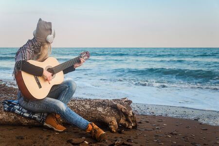The girl in the headphones on the seashore plays the guitarの写真素材