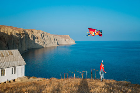 Young girl launches a colorful kite on the sea coast
