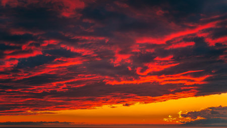 Blood red bright sunset in the mountains above the seaの写真素材