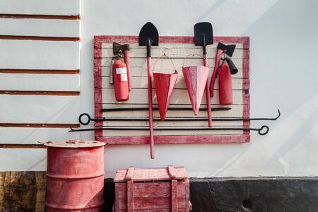 Red fire shield with fire extinguishing tools, covered in shabby, old, cracked paintの写真素材