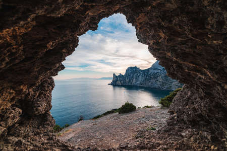 View from the rocky grotto to the sea bay at sunsetの写真素材