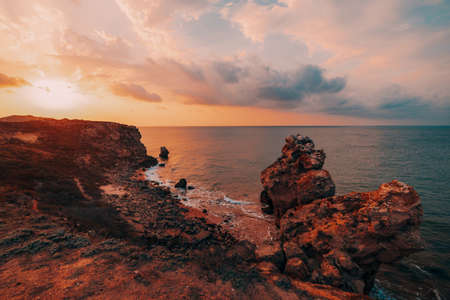 Amazing sunset at sea, beauty of nature. Scenic view of the sea, rocky coastline and sandy beach, golden sky and sun, outdoor travel background. General's beaches. Crimea.の写真素材